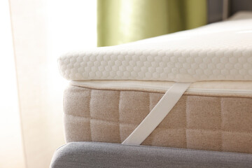 White memory foam mattress topper on grey bed indoors, closeup