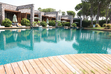 Outdoor swimming pool with wooden deck, umbrellas and sunbeds at resort