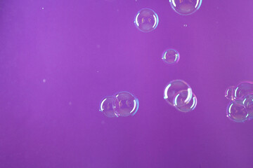 Beautiful transparent soap bubbles on violet background, space for text