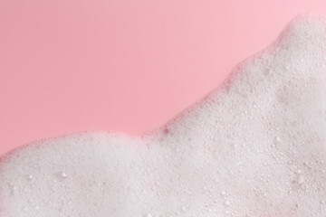 White fluffy foam on pink background, top view. Space for text