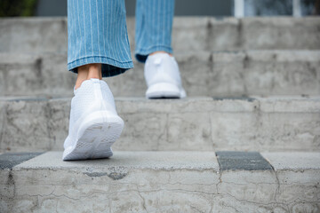 In the city, a businesswoman climbs the stairs in sneakers, signifying her commitment to success....