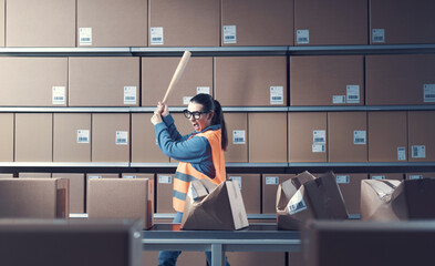 Angry aggressive worker smashing boxes with a bat