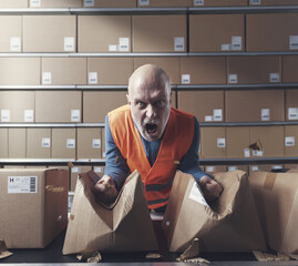 Furious rebellious worker tearing boxes at the warehouse