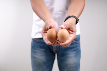 Asian man holding two eggs. Male testicle health and swollen balls concept