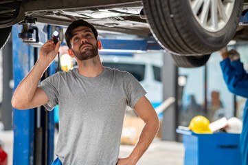Portrait photo of professional look Caucasian vehicle service technician standing under car...