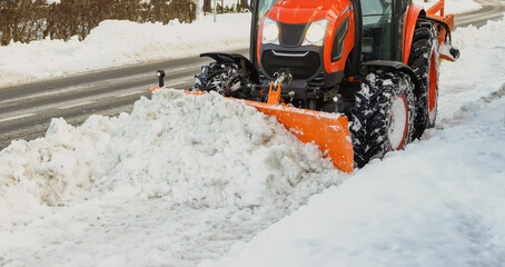 The tractor cleans the sidewalk from the pedestrian path in winter
