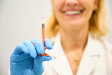 Aesthetic doctor woman is holding a syringe with Botox in a clinic.