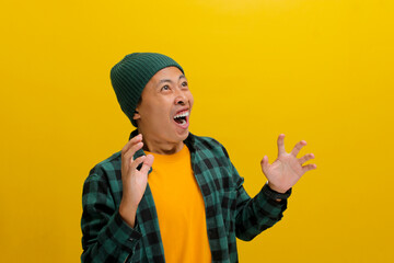 Excited young Asian man, dressed in a beanie hat and casual shirt, loudly exclaims WOW, his hands...