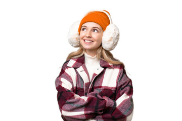 Young  English woman wearing winter muffs over isolated background looking up while smiling