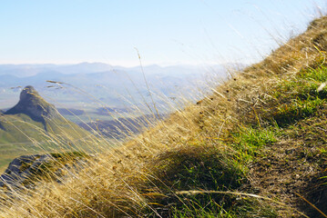 Landscape taken from the trail along Mount Sedlena Greda in Durmitor National Park: close-up of yellowed grass, the Stozina peak and other mountains of northern Montenegro out of focus.