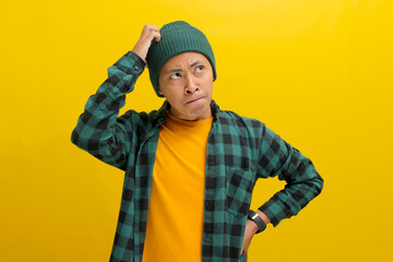 Puzzled young Asian man, dressed in a beanie hat and casual shirt, is depicted in a moment of...