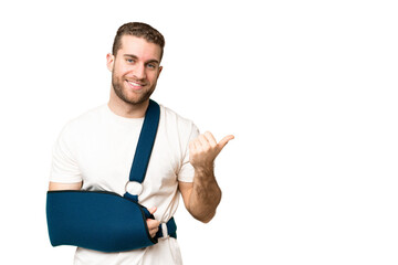 Young handsome blonde man with broken arm and wearing a sling over isolated chroma key background...