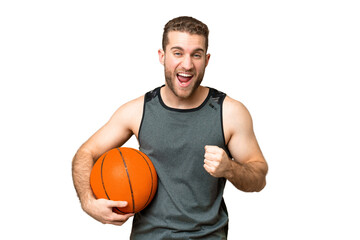 Handsome young man playing basketball over isolated chroma key background celebrating a victory in...