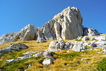View of Zupci - part of Sedlena Greda mountain in Durmitor National Park, Montenegro. Picturesque gray rocks looming over a grassy mountainside.