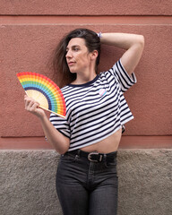 Transgender woman portrait with a rainbow fan posing sexy. Concept of pride expressing support for...