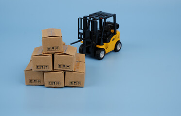 Heap of carton boxes and forklift truck on blue background. Shipping and cargo concept.