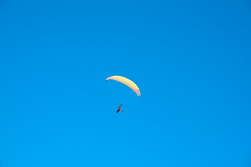 Paraglider with motor over the zenith of the observer and with blue sky in the background