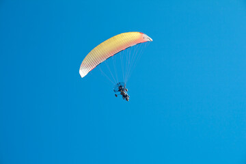 Paraglider with motor over the zenith of the observer and with blue sky in the background