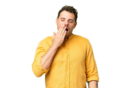 Brazilian man over isolated chroma key background yawning and covering wide open mouth with hand
