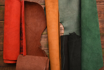 Colorful pile of leather rolled up pieces on the tanner table top view. Leather craft concept...