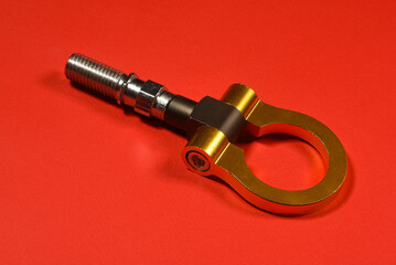 Sport car tow hook on the red flat lay background close up with copy space.