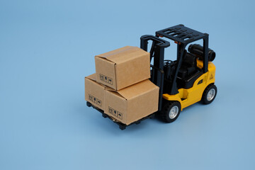 Yellow forklift track with three carton boxes on blue background
