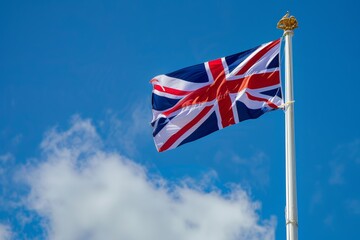 Naklejka premium Union Jack flag flying against a clear blue sky, representing British heritage and pride. British flag