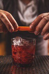 Bartender twisting orange peel over a craft cocktail