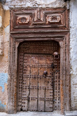 Traditional moroccan ancient wooden door with metal knocker and studs reinforcements. Fez, Medina of the old city Morocco

