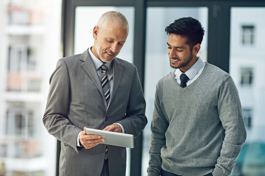 Mature, man and young male for mentor, tablet and pointing in office for advice in business or workplace. Employee, intern and technology in meeting for brainstorming, ideas and plan in corporate
