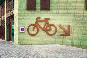 Bicycle sign on green brick building in Amsterdam, Netherlands.