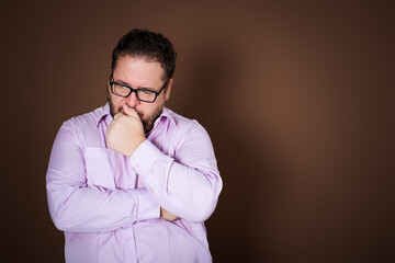 Anger and aggression. Upset fat man posing on a brown background.