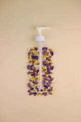 on a beige background, a dispenser and flowers in the form of a bottle or spray