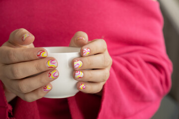 Pastel softness colorful manicured nails. Woman holding white cup of coffee or tea showing her new...