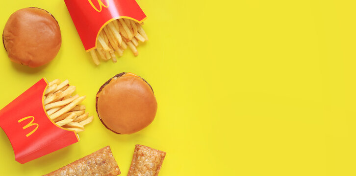 Kyiv, Ukraine - January 31, 2024: French fries in paper packaging, cherry pies and cheeseburgers on a yellow background, top view. McDonald's Corporation is the world's largest fast food restaurant.