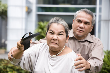 Angry old senior woman holding slipper and being ready to slap or hurt you, concept image of...