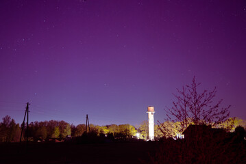 northern lights, where the water tower, trees and power lines can be seen in the distance