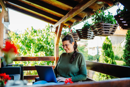 One young caucasian woman is working on her laptop from home on her balcony