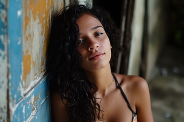Naklejka premium Portrait of a serene young woman with curly hair leaning against a textured wall