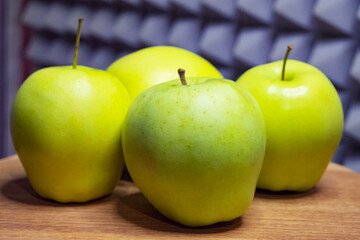 Green apples on a wooden table, grey patterned backdrop.