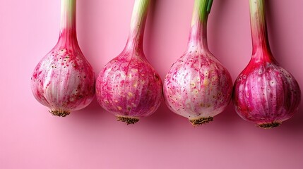  Three onions sit atop a pink surface alongside a green stem Two of the onions display yellow spots