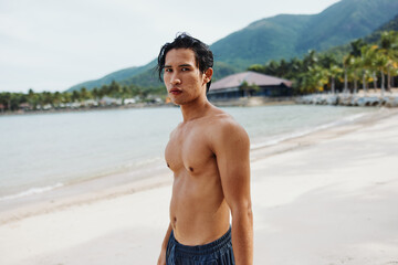 Smiling Asian Man Enjoying Tropical Beach Vacation with Muscular Torso