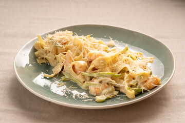 Traditional Italian fettuccine pasta with cream sauce, shrimp and zucchini served on a plate