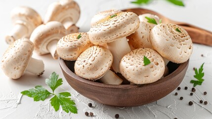 Organic white button mushrooms in a wooden bowl with parsley and peppercorns on a white background.