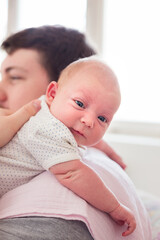 Young father burping a newborn baby girl after feeding