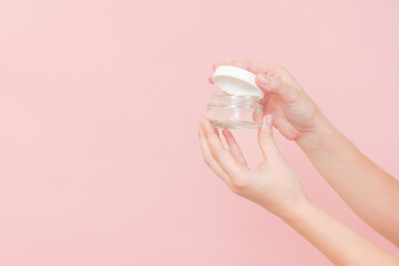 Glass clear cosmetics jar for face or skin cream in hand. Package for cosmetic beauty product,...