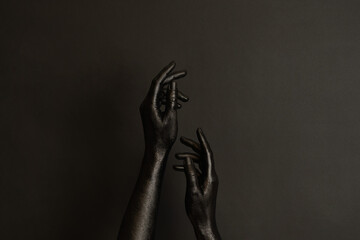 Woman's hands with black paint on her skin on dark background. High Fashion art concept