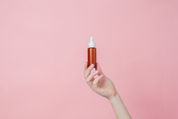 Serum glass brown bottle (essential oil) with pipette in hand. Product cosmetic advertising