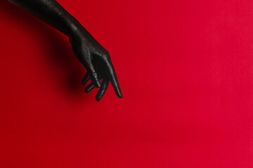 Black color painted woman's hands on her skin with red background. High Fashion art concept