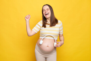 Overjoyed excited Caucasian pregnant woman in casual clothing posing isolated over yellow...